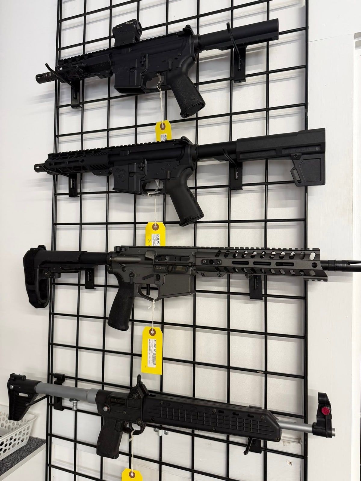 AR-style pistols and a folding carbine hanging on the gun wall with price tags at New Georgia Pawn
