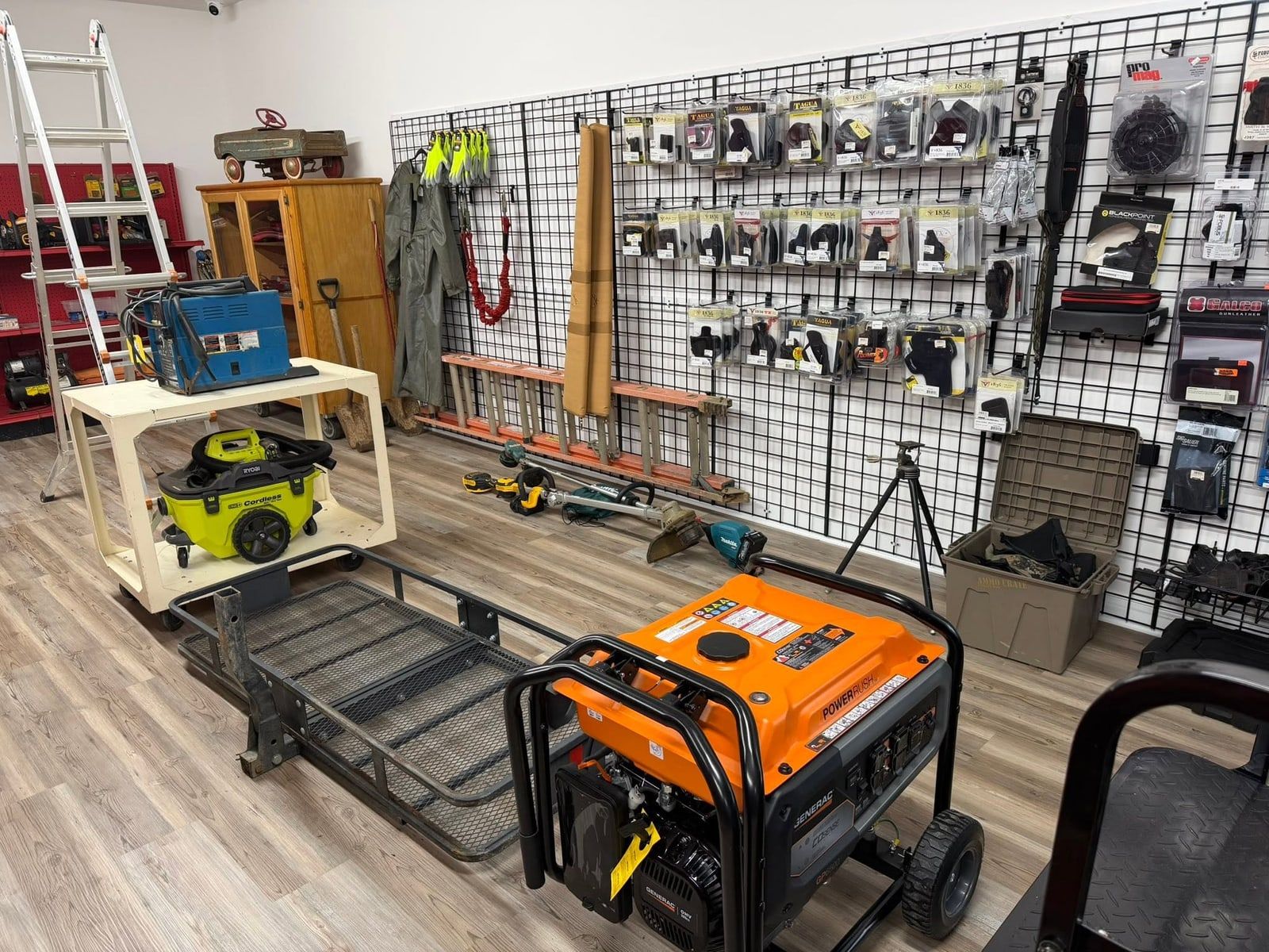 The shop floor at New Georgia Pawn with a portable generator, shop vacuum, ladders, power tools, and a wall of holsters and accessories